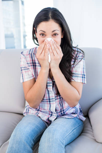 istock Pretty brunette looking at camera and sneezing on couch 667438842