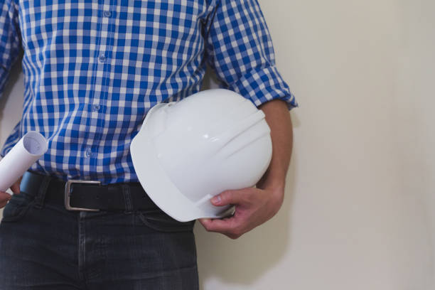 architect or engineer man with blueprint and white construction safety helmet at office workplace