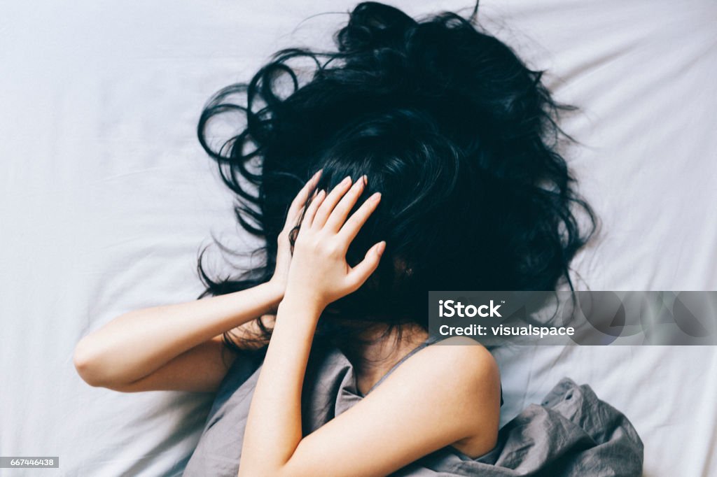 Young woman distressed Young woman covering her face with hair and hands. Women Stock Photo