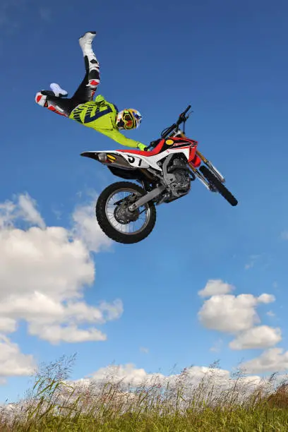 Man performing motorcycle stunt above hill