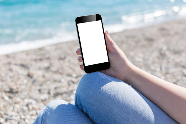 istock Hand holding a smartphone on a beach 667465300