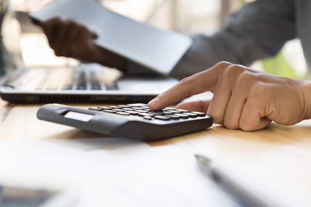 istock Businessman Analyzing financial data on digital tablet and counting on calculator 667465582