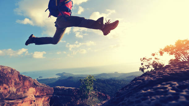istock jumping over precipice between two rocky mountains at sunset 667470730