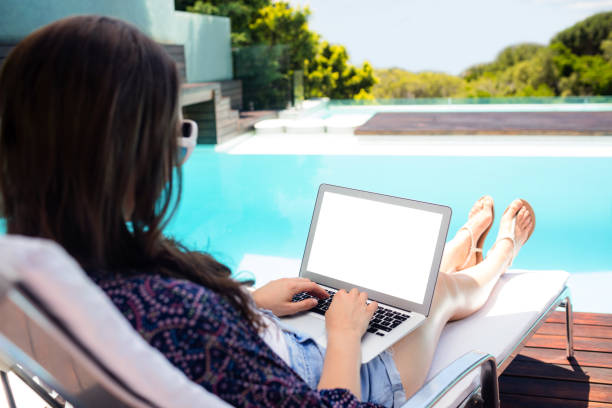 istock Woman sitting on deckchair using laptop 667470744