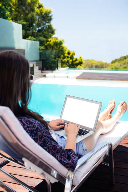 istock Woman sitting on deckchair using laptop 667470892