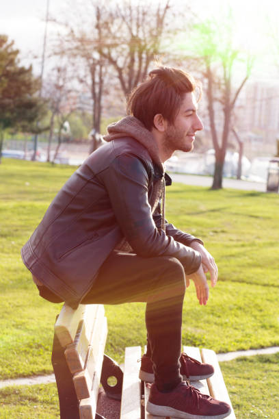 istock Young man daydreaming on the bench in the park 667476860