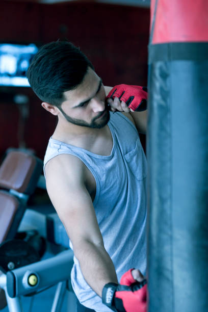 istock Boxer striking the punching bag at gym 667485606