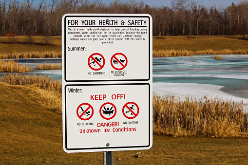 Warning signs around storm drainage pond.