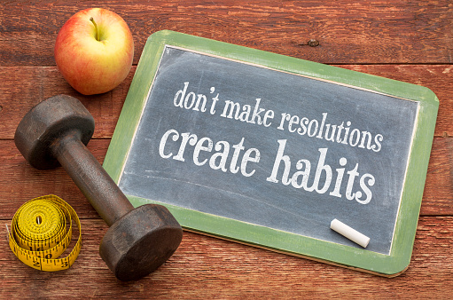 Do not make resolutions, create habits - advice on a vintage slate blackboard with a dumbbell