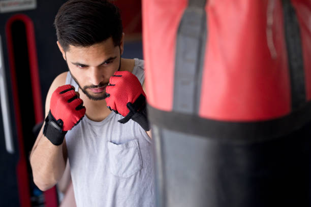 istock Boxer striking the punching bag at gym 667498574