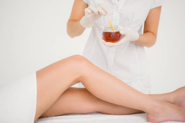 istock Therapist waxing womans leg at spa center 667499710