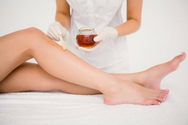istock Therapist waxing womans leg at spa center 667499832
