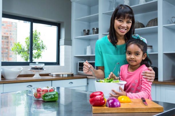 istock Smiling mother washing salad with her daughter 667503380