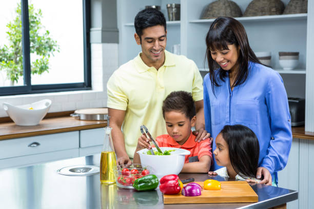 istock Happy family preparing salad in the kitchen 667506104