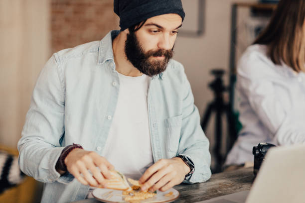 hipster comendo um sanduíche de clube - casual teamwork journalist editor - fotografias e filmes do acervo