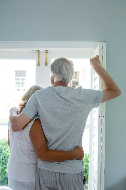 istock Senior couple looking through window at home 667509782