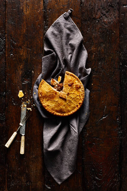 Venison pie on rustic background Top view of venison pie on tablecloth on rustic background with knife and fork meat pie stock pictures, royalty-free photos & images