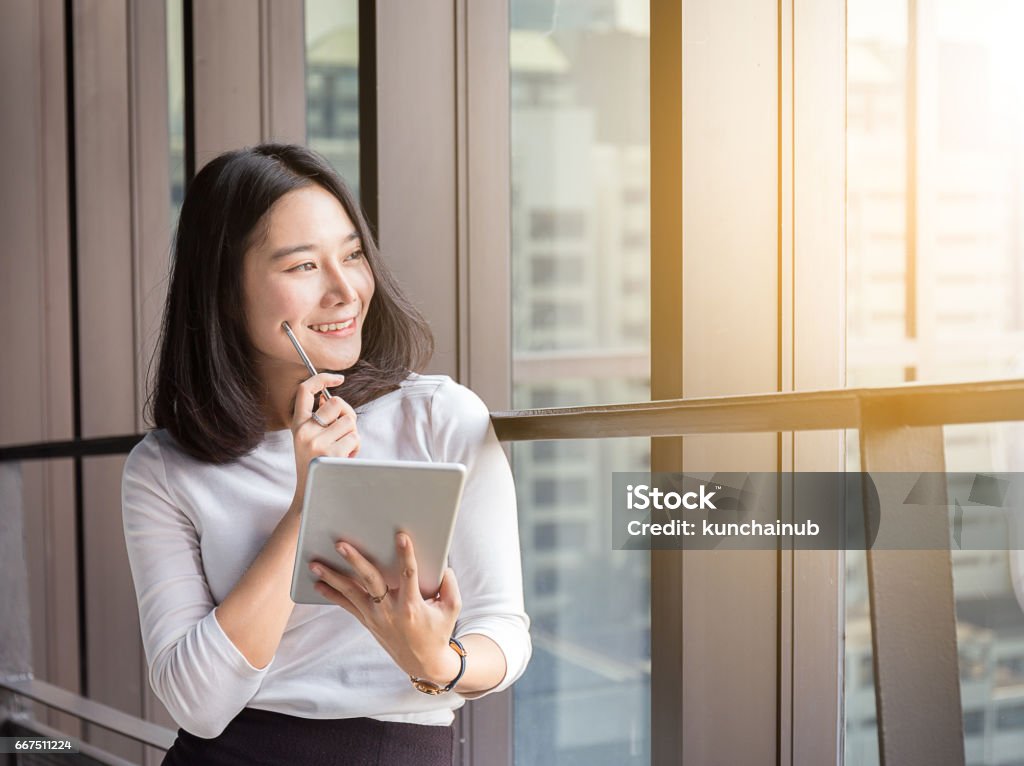 smile business woman is thinking with tablet in modern office Digital Tablet Stock Photo