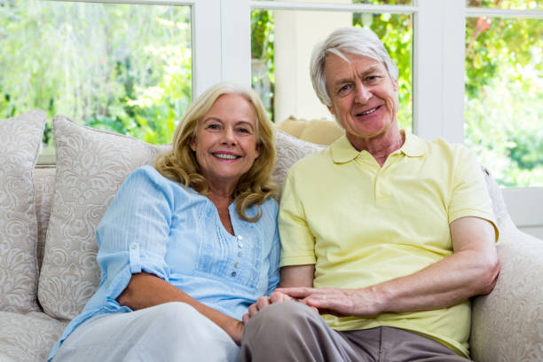 istock Smiling senior couple sitting on sofa at home 667514686