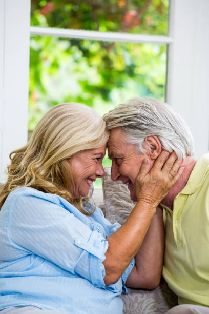 istock Romantic senior couple emracing while sitting on sofa 667518126