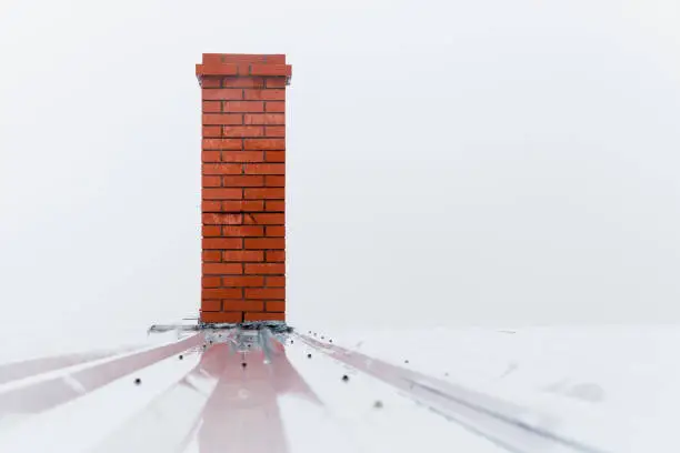Chimney made of red bricks over foggy white sky