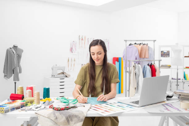 fashion designer drawing a concept a young fashion designer drawing at the desk in her showroom fashion designer photos stock pictures, royalty-free photos & images