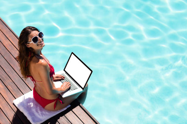 istock Woman using her laptop on the pool edge 667539790