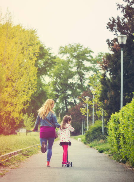 istock Mother with daughter riding a kick scooter 667545086
