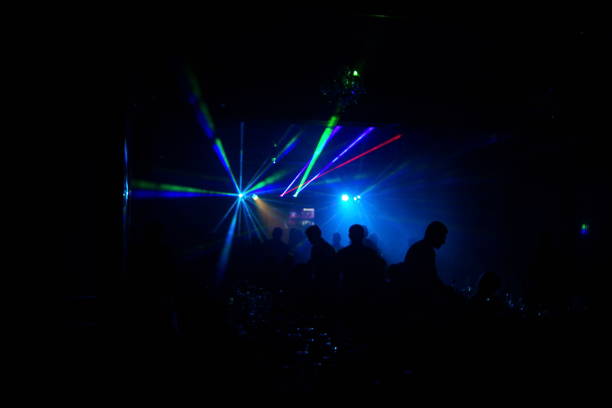 istock Deejay silhouette on a stage with big disco ball at background with the colorful rays on it 667551120