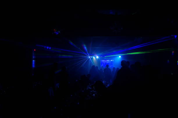 istock Deejay silhouette on a stage with big disco ball at background with the colorful rays on it 667551168