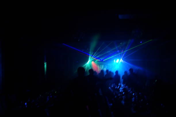 istock Deejay silhouette on a stage with big disco ball at background with the colorful rays on it 667551232