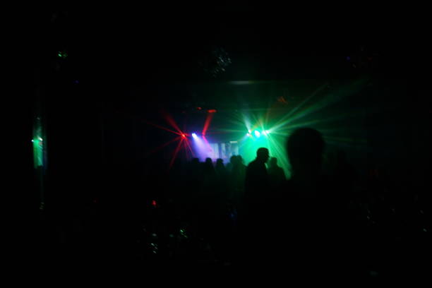 istock Deejay silhouette on a stage with big disco ball at background with the colorful rays on it 667551234