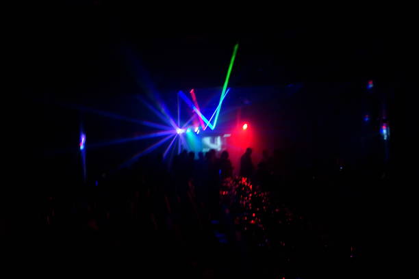 istock Deejay silhouette on a stage with big disco ball at background with the colorful rays on it 667551256