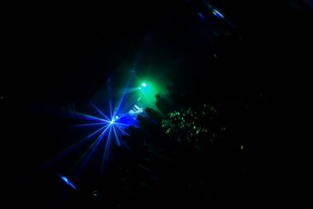 istock Deejay silhouette on a stage with big disco ball at background with the colorful rays on it 667551278