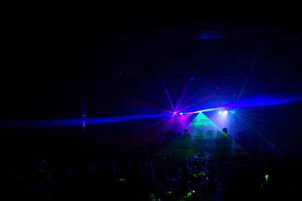 istock Deejay silhouette on a stage with big disco ball at background with the colorful rays on it 667551340