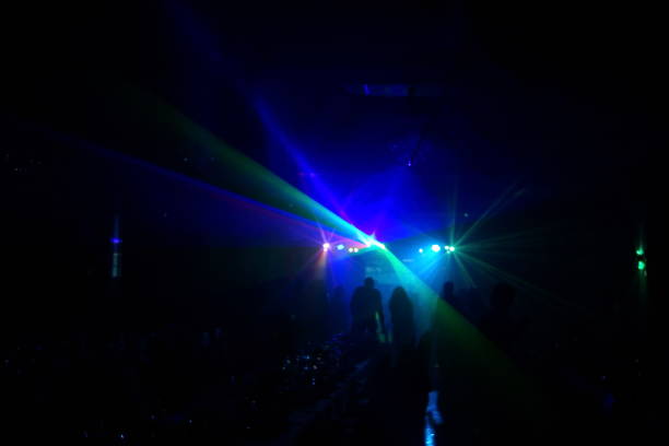 istock Deejay silhouette on a stage with big disco ball at background with the colorful rays on it 667551358