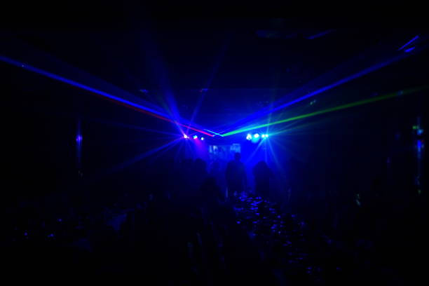 istock Deejay silhouette on a stage with big disco ball at background with the colorful rays on it 667551396