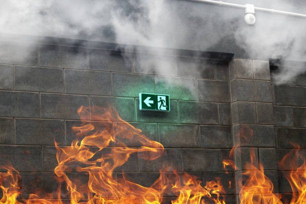 uscita antincendio di emergenza sul muro di pietra con fuoco e fumo - fire button foto e immagini stock