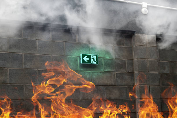 Saída de emergência de incêndio na parede de pedra com fogo e fumaça - foto de acervo