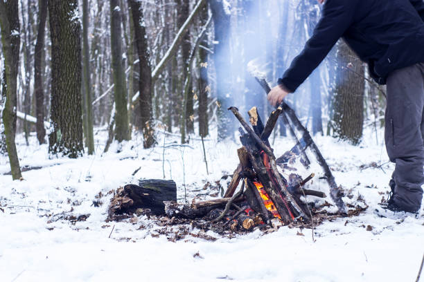 istock man warming his hands around a campfire in the forest 667557728