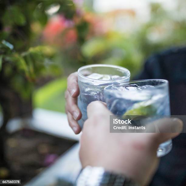 Celebration Concept With Hand Closeup Of A Couple Celebrating The Beginning Of Their Vacations With Each A Gin Tonic Stock Photo - Download Image Now