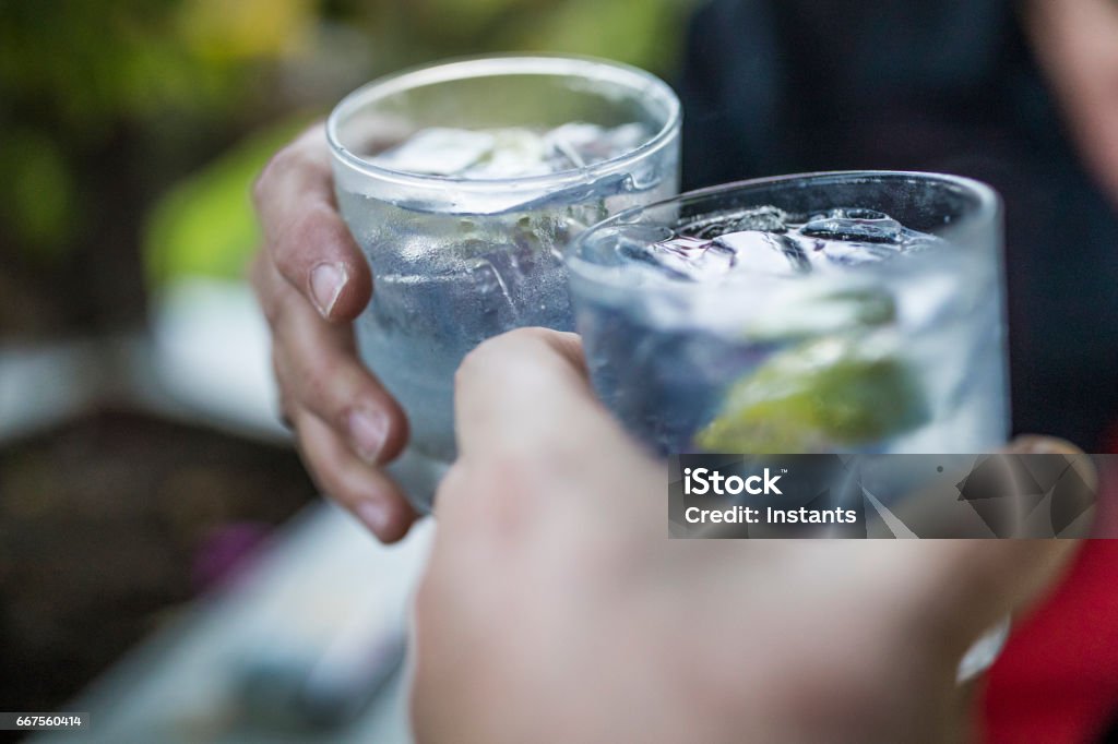 Celebration concept with hand close-up of a couple celebrating the beginning of their vacations with each a gin & tonic. Shot with a 35mm. Gin Stock Photo