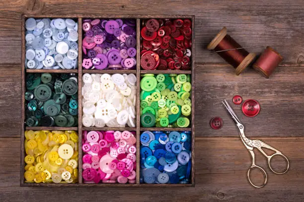 Photo of Colourful buttons with needle, thread and scissors
