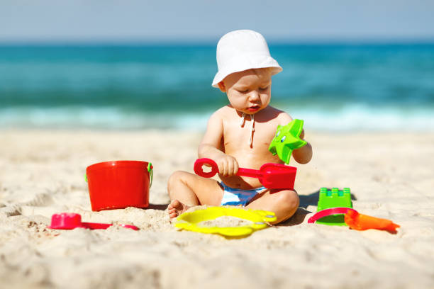 istock baby boy playing with toys and sand on beach 667571430