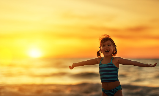 Happy child girl in bikini on the beach in the summer sea