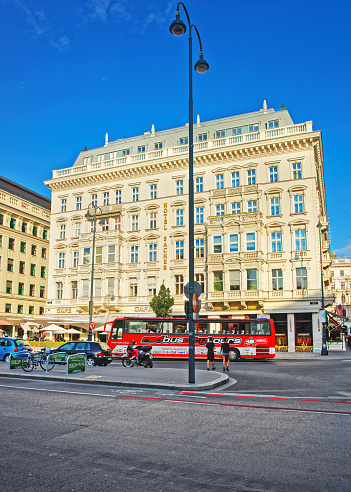 Vienna, Austria - August 31, 2013: Red excursion bus at Sacher Hotel on Albertinaplatz in Vienna, Austria. People on the background.