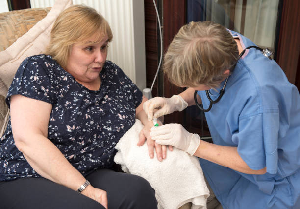 enfermera poniendo una aguja intravenosa en la mano de un paciente - intravenous infusion fotografías e imágenes de stock