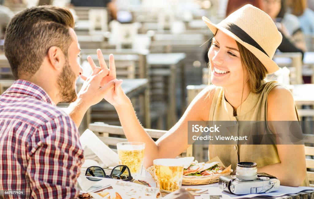 Coppia innamorata che si diverte al beer bar durante un'escursione di viaggio - Giovani turisti felici che si godono il momento felice al ristorante di cibo di strada - Concetto di relazione con focus sul viso da ragazza sul filtro caldo e luminoso - Foto stock royalty-free di Relazione di coppia