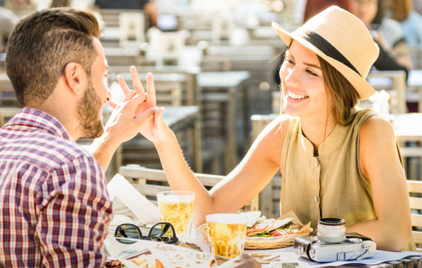 couple in love having fun at beer bar on travel excursion - young happy tourists enjoying happy moment at street food restaurant - relationship concept with focus on girl face on warm bright filter - dating restaurant dinner couple imagens e fotografias de stock