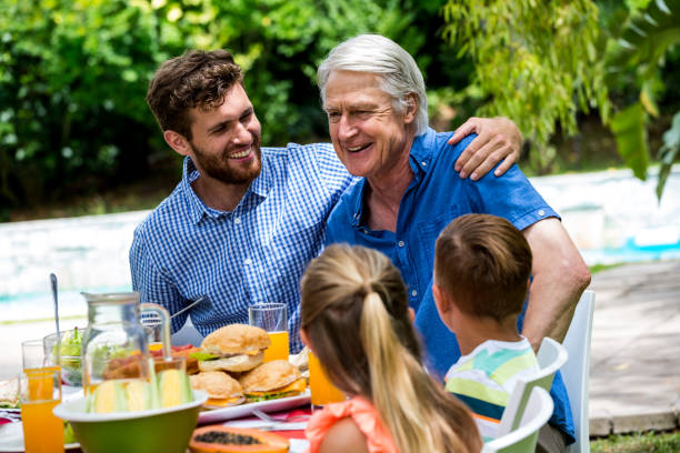 istock Father and son with children at dinning table in lawn 667578390